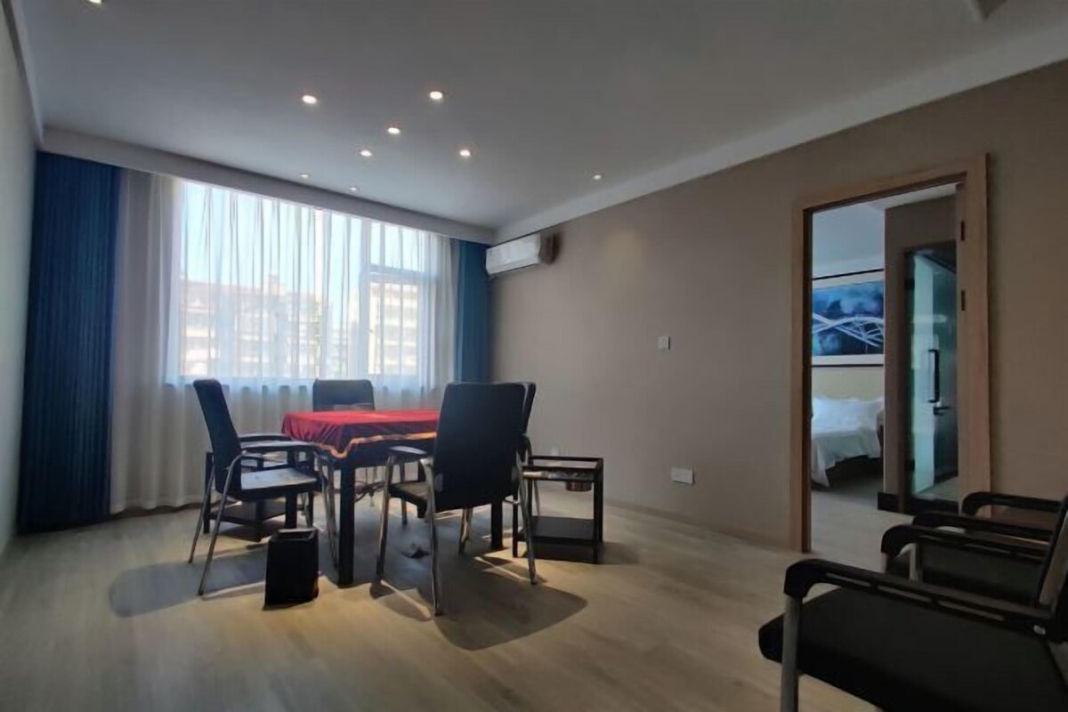 A modern hotel room with a dining area, a bed, and a view of the cityscape.