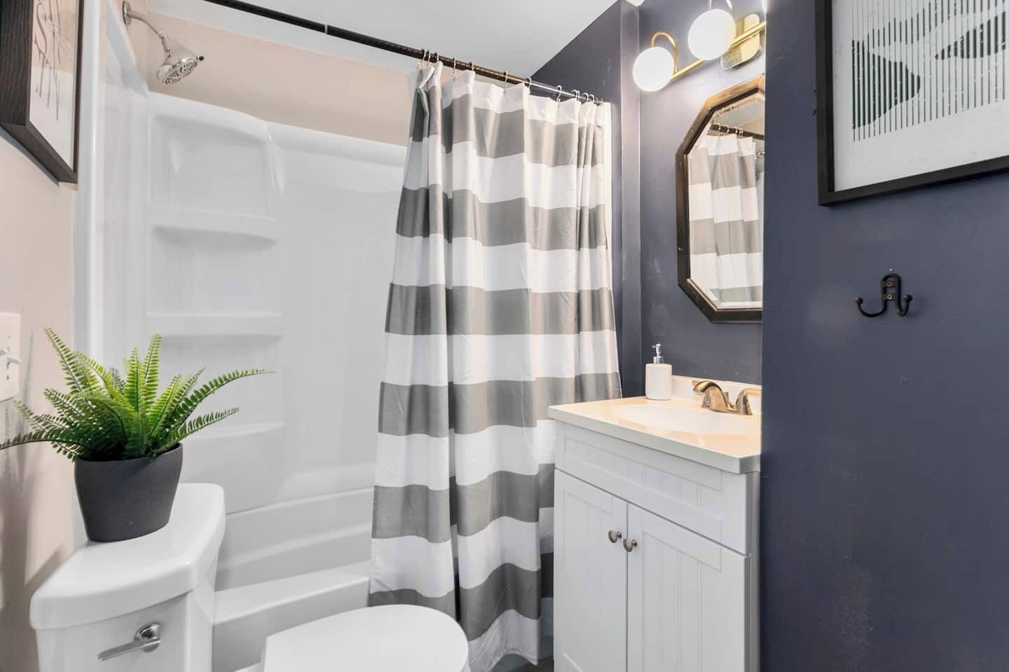 Een badkamer met douche, toilet, wastafel en een potplant.