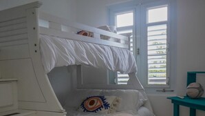 Une chambre avec un lit superposé, une fenêtre, une petite table avec une balle et un tapis sur le sol.
