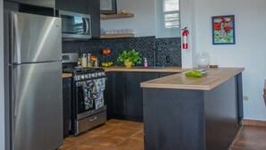 Une cuisine moderne dotée d’appareils électroménagers en acier inoxydable, d’un îlot central et d’un luminaire suspendu de couleur verte.