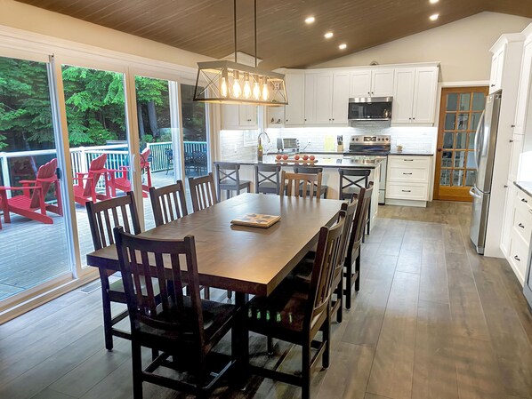 A spacious kitchen with white cabinets, a large island, and a dining area with wooden chairs.