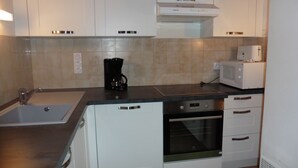 A kitchen with white cabinets, a black coffee maker, a white microwave, and a stove. - House 5 minutes from the beach and shops (La Brée-les-Bains)