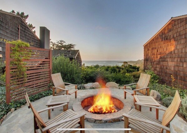 Relax by the fire pit surrounded by Adirondack chairs in a tranquil ocean-view setting.