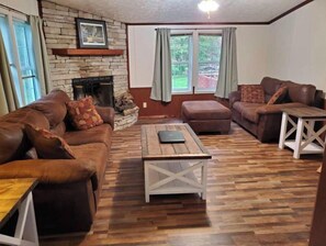 Cozy living room with a brick fireplace, two sofas, and a wooden coffee table.