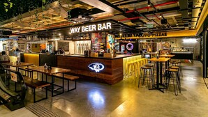 A modern bar area with a neon sign, wooden tables, and a pizza counter. - 450m Shopping | Dining | Pool #CA25 (Florianópolis)