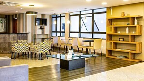 A modern hotel lobby with a bar area, seating arrangements, and a large window providing natural light. - Rooftop Pool with Sea and Bridge Views #CA22 (Florianópolis)