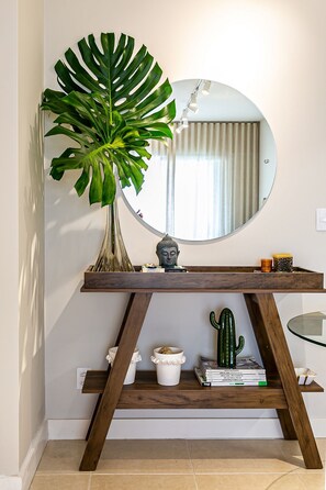 A wooden console table with a large mirror, a potted plant, and decorative items.