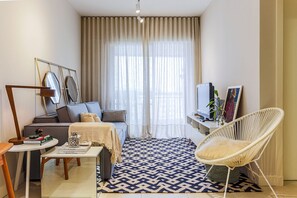 A modern living room with a sofa, a white chair, a coffee table, and a TV. - WI-FI 250MB | Condominium with Pool #CA10 (Florianópolis)