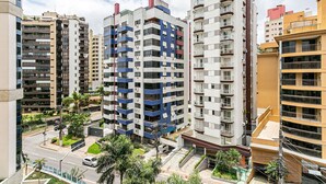 A high-rise residential building with multiple balconies, a central courtyard, and a street view. - WI-FI 120MB | 120m from Beiramar Shopping #CA31 (Florianópolis)