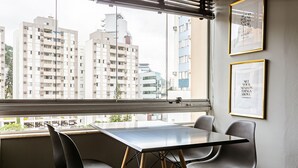 A modern interior with a dining table and chairs, large windows with a city view, and framed inspirational quotes on the wall. - WI-FI 120MB | 120m from Beiramar Shopping #CA31 (Florianópolis)