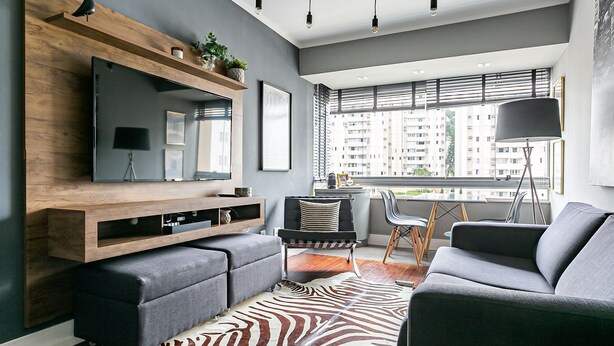 A modern living room with a large flat-screen TV, a wooden TV stand, grey sofas, a zebra-patterned rug, and a view of a cityscape through large windows. - WI-FI 120MB | 120m from Beiramar Shopping #CA31 (Florianópolis)