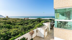 A modern building with a glass facade overlooking a beach. - SEA VIEW | Balcony with Barbecue #IA09 (Florianópolis)