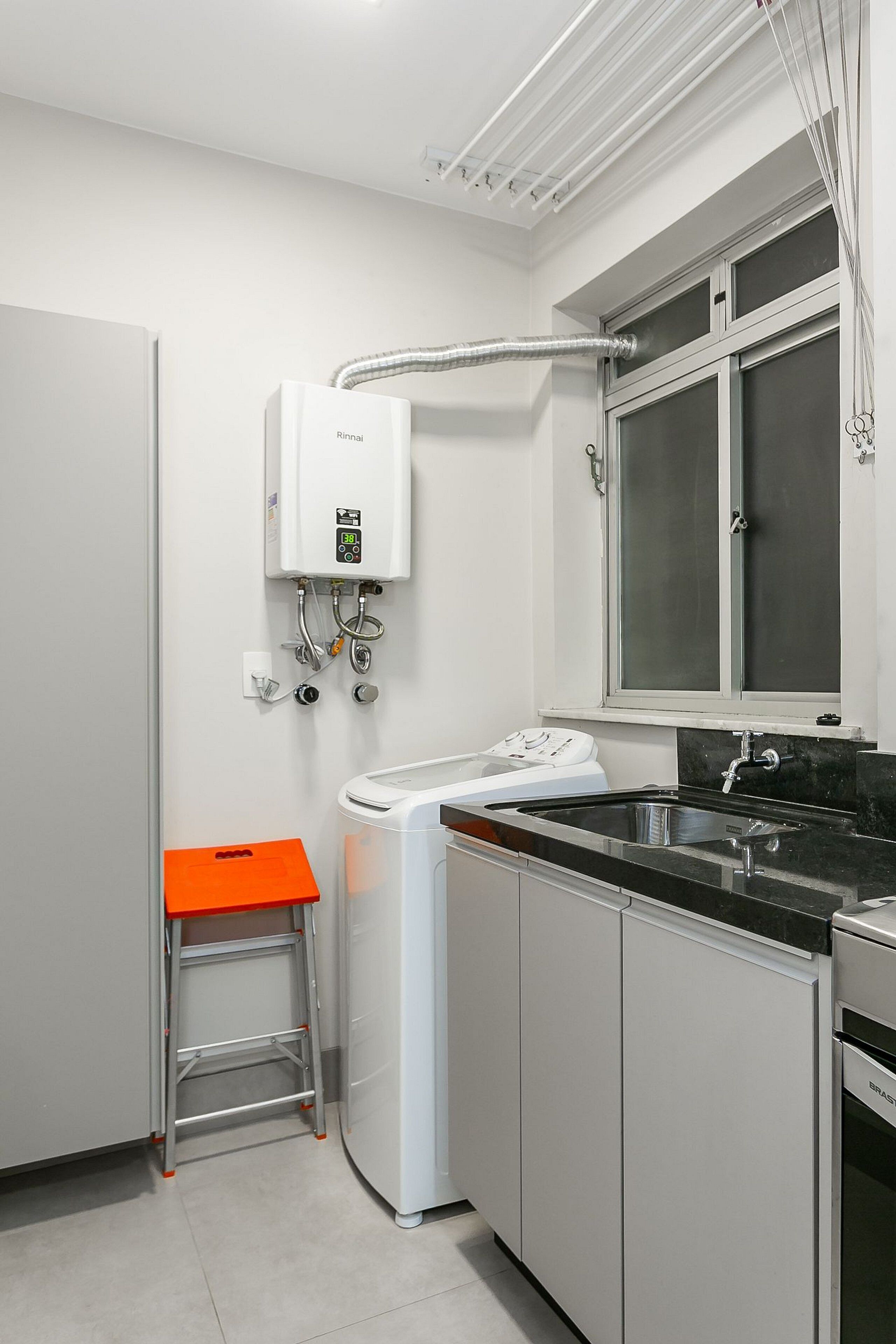 Une cuisine compacte équipée d’un lave-linge intégré, d’un évier et d’une fenêtre située au-dessus du plan de travail.