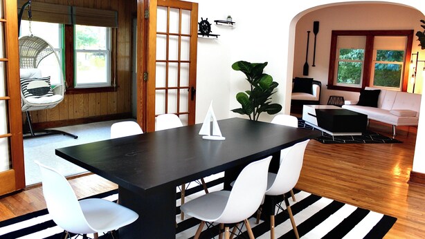 A dining area with a black table, white chairs, a hanging chair, and a potted plant. - Fun Haven! 2 Units in 1 house for private gatherings and games (South Haven)