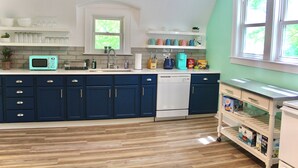 A kitchen with blue cabinets, a white dishwasher, and a window with a view of greenery. - Fun Haven! 2 Units in 1 house for private gatherings and games (South Haven)
