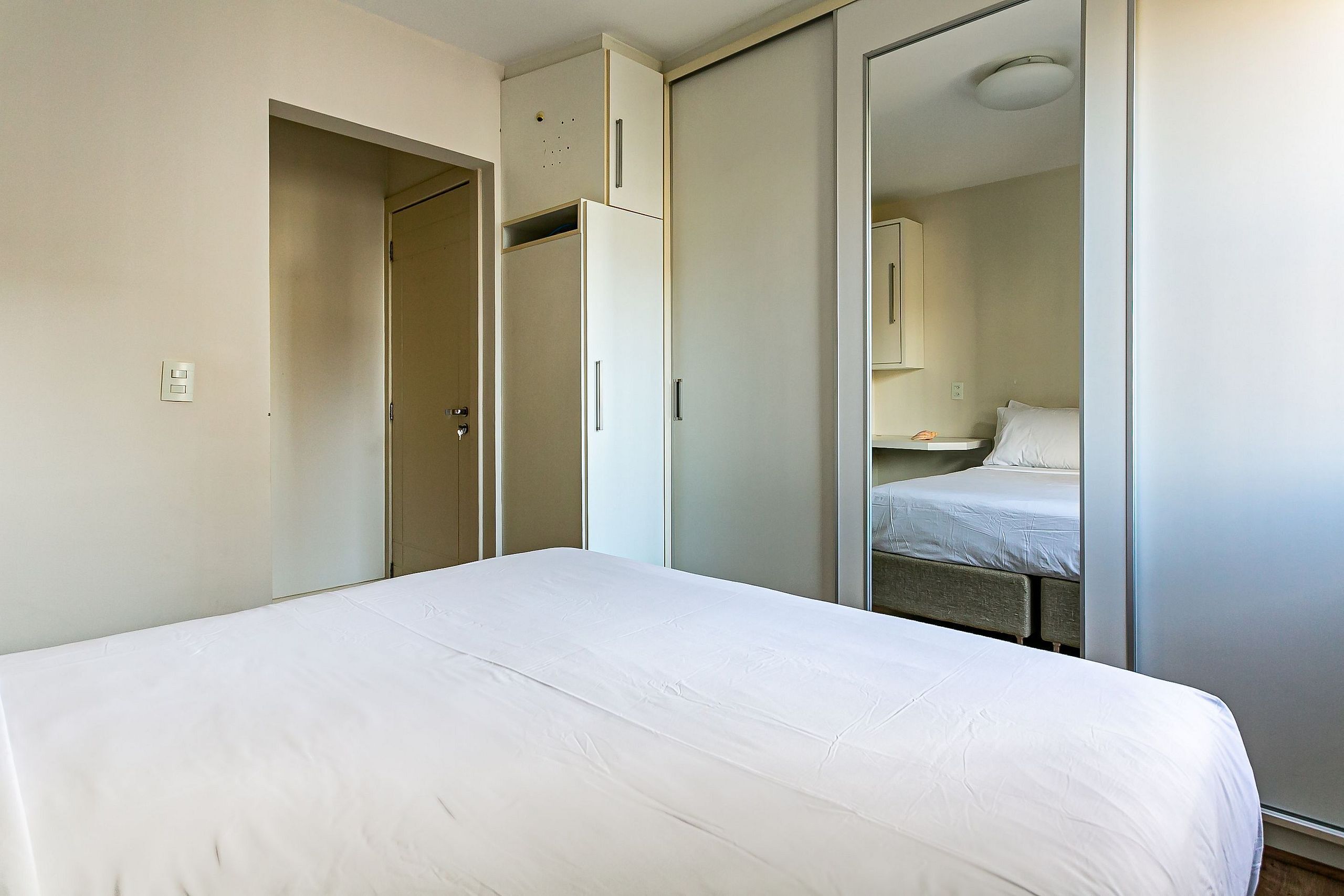 Une chambre à coucher avec un lit, une armoire et un miroir.