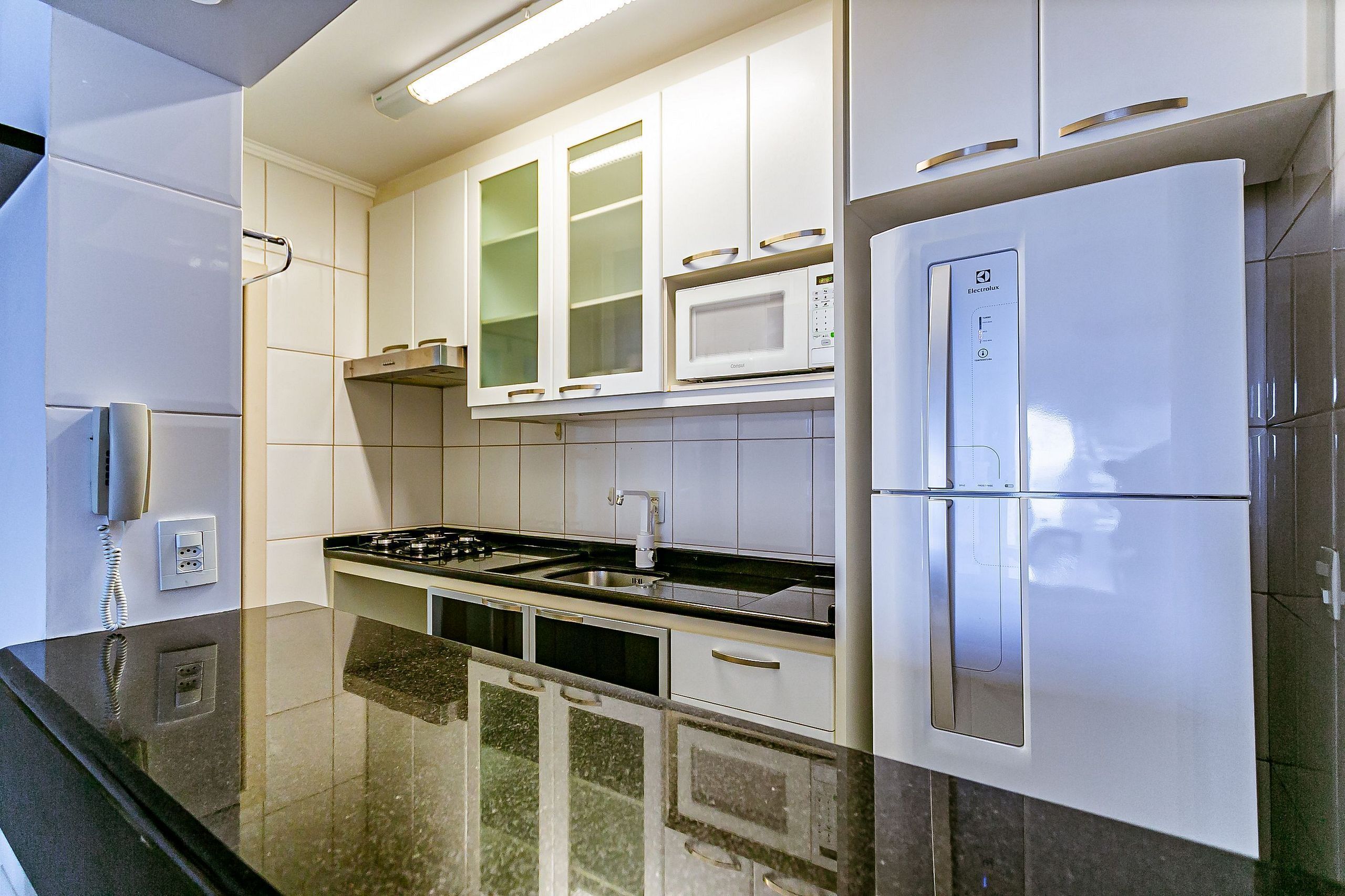 Une cuisine moderne avec des meubles blancs, un réfrigérateur en acier inoxydable, un four à micro-ondes et une cuisinière à gaz.