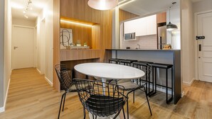 A modern kitchen with a central island, black wire chairs, and a pendant light. - WI-FI 350MB | 200m from Beiramar Shopping #CA29 (Florianópolis)