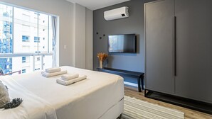 Ein modernes Schlafzimmer mit einem großen Bett, einem an der Wand montierten Fernseher und einem Kleiderschrank.