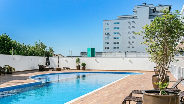 Ein Pool auf dem Dach mit Holzterrasse, Liegestühlen und Topfpflanzen.