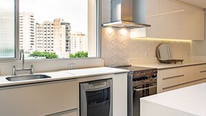 A modern kitchen with a built-in dishwasher, stove, and a window offering a city view. - WI-FI 240MB | Downtown Florianópolis #CA19 (Florianópolis)