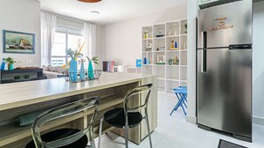 A modern kitchen with a stainless steel refrigerator, wooden island, and clear chairs.