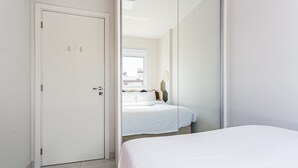 A bedroom with a bed, a door, and a window.