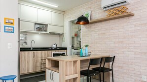 A modern kitchen with white cabinets, a wooden island, and a black pendant light.