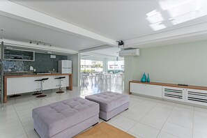 A modern kitchen with a bar area, two cushioned seating areas, and a view of the outdoors. - 400m from the beach | Pool | Gastronomy #IA10 (Florianópolis)