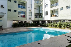 Um edifício moderno com piscina, varandas e aparelhos de ar condicionado.
