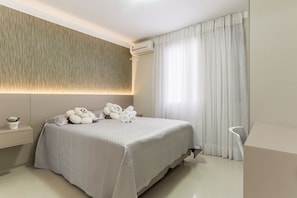 Une chambre moderne avec un grand lit, une table de chevet avec une lampe et un climatiseur fixé au mur.