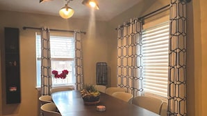 A dining area with a dark wooden table, beige chairs, and a potted plant. - Close to Old Town Alexandria And All Things DC (Alexandria)