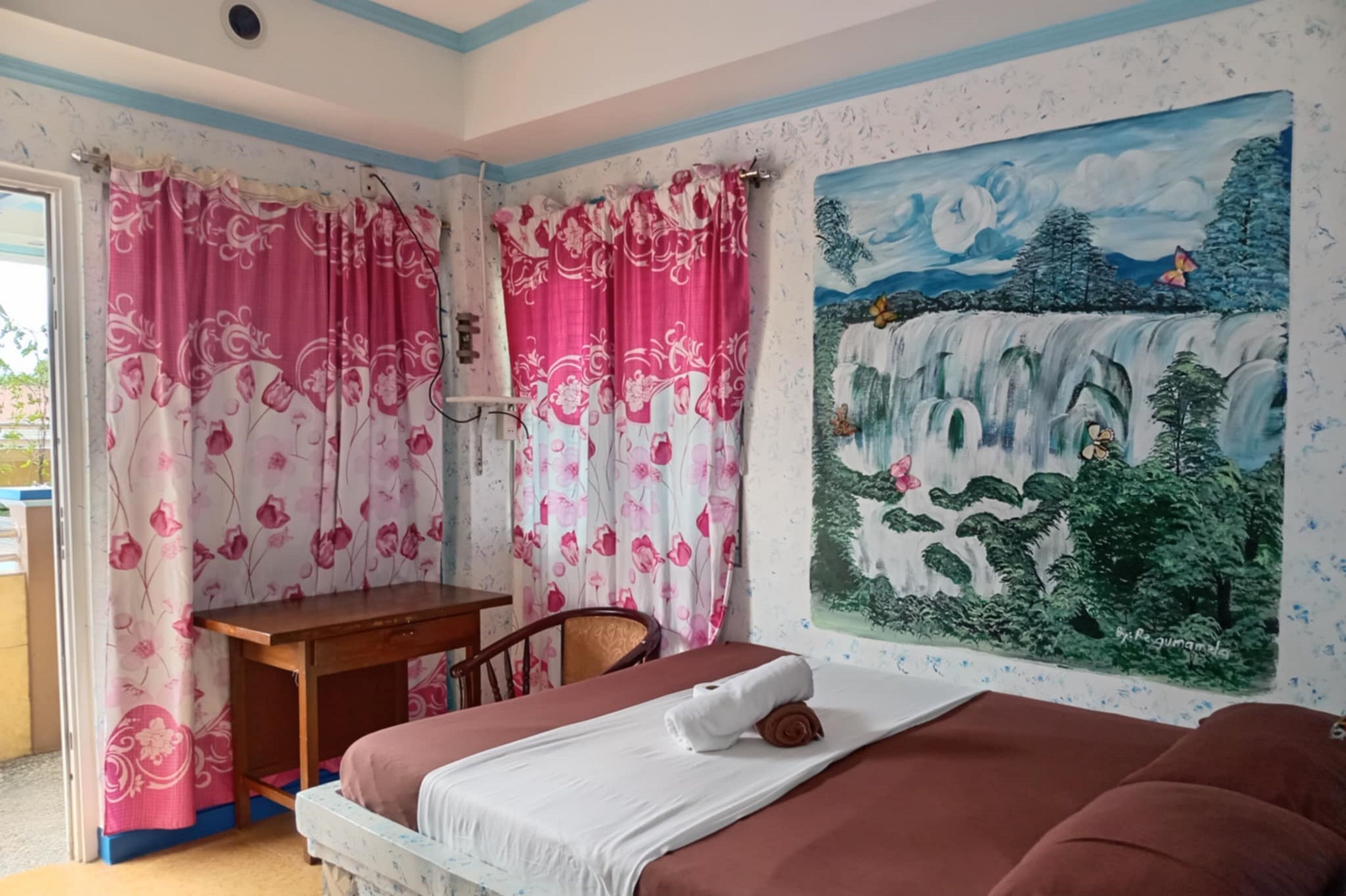 Ein Schlafzimmer mit einem Bett, einem Schreibtisch und einem Bild eines Wasserfalls.