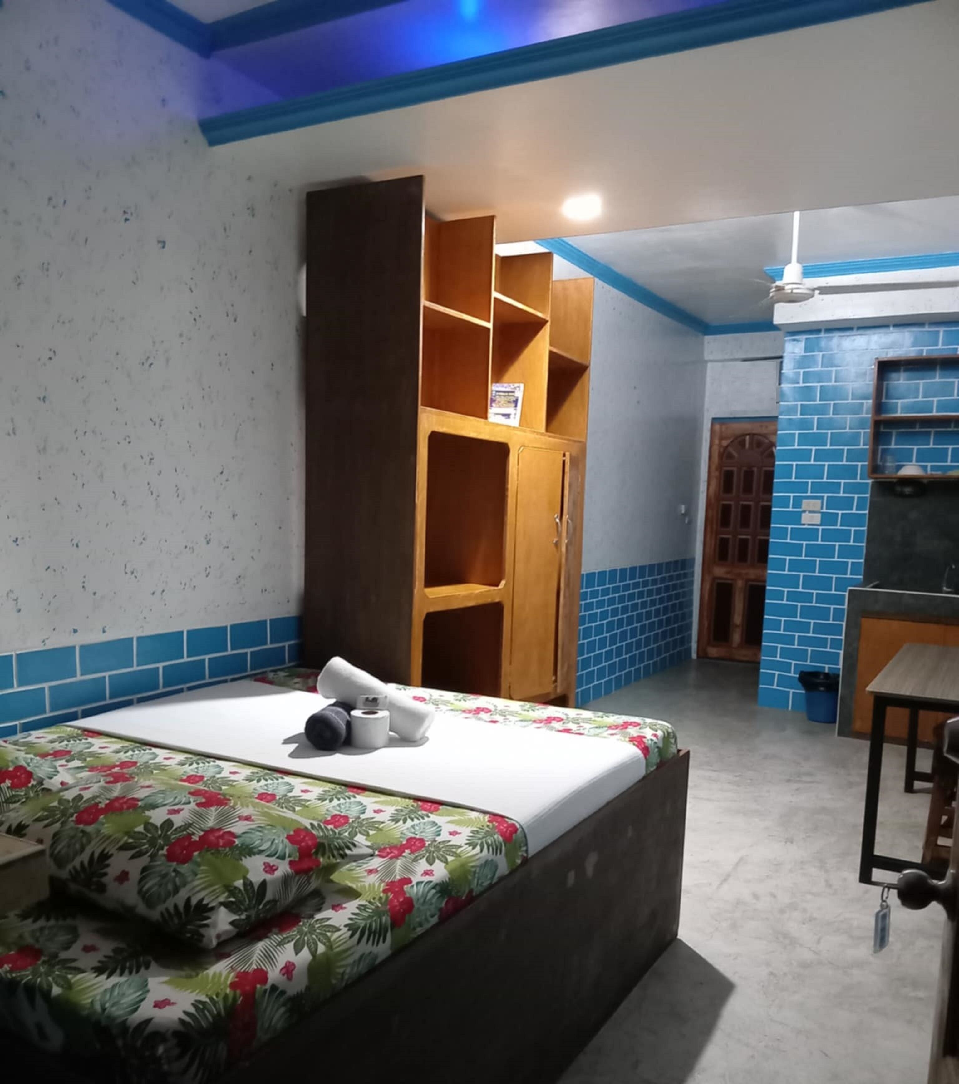Une pièce comprenant un lit, une armoire, une petite table et un mur recouvert de carreaux bleus.