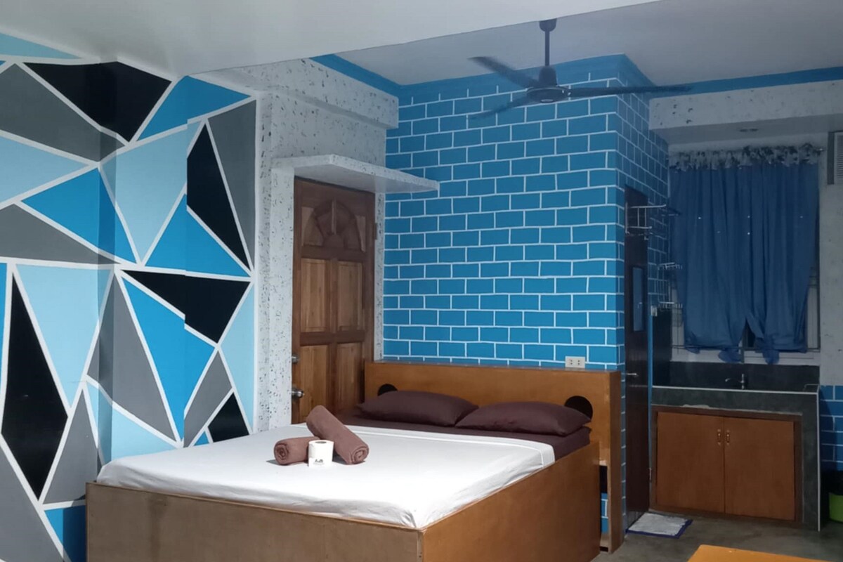 A bedroom with a wooden bed, a blue brick wall, and a geometric wall design.