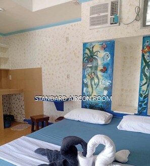 A standard aircon room with a bed, pillows, a painting, and a towel sculpture. - Danielas Place (Angeles City)