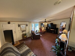 A living room with a sofa, a TV, and a ceiling fan.