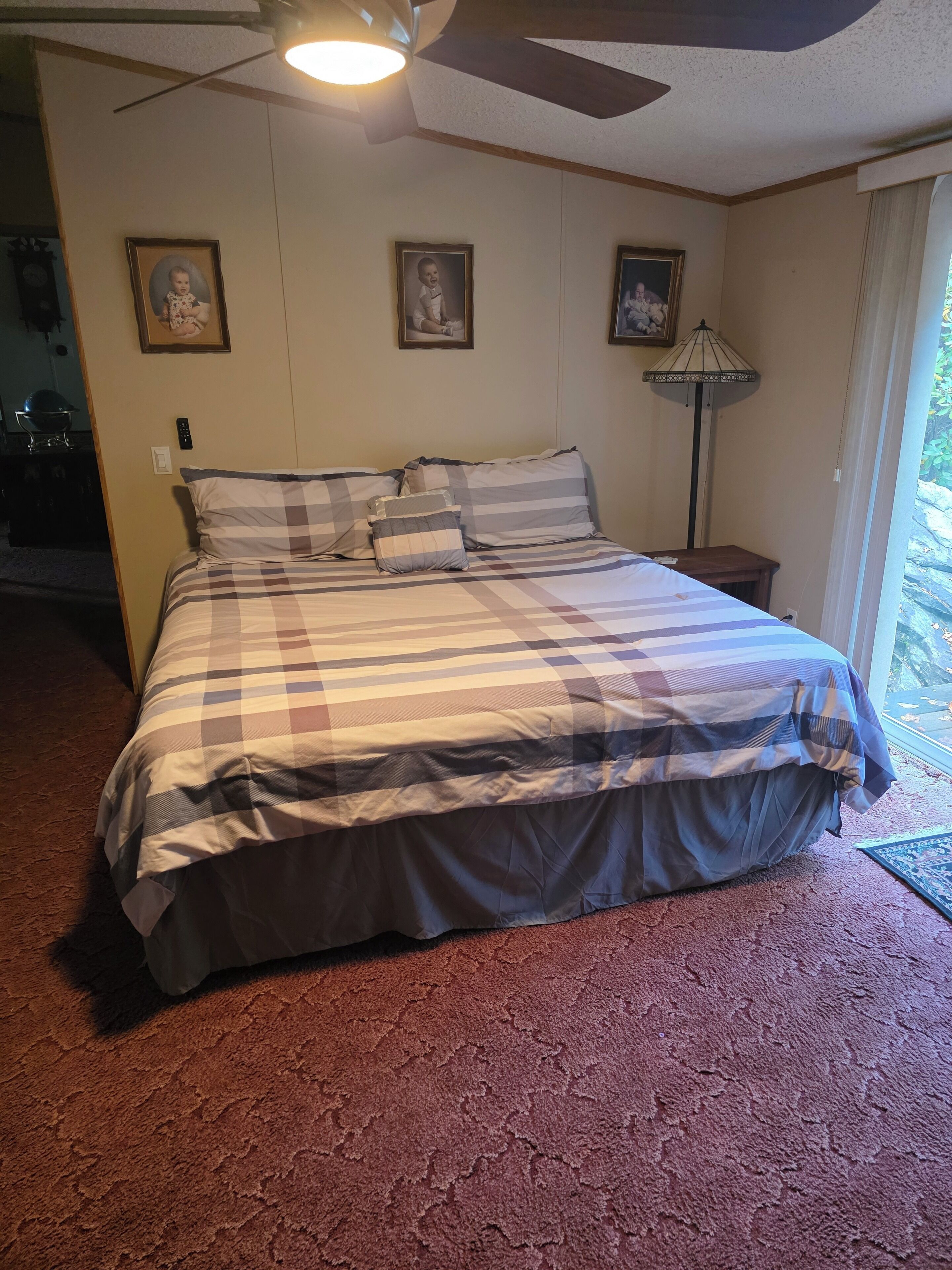 A bedroom with a large bed, a ceiling fan, and three framed pictures on the wall.