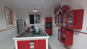 Cuina amb illa central, armaris vermells i nevera.