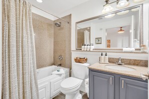 A modern bathroom with a bathtub, toilet, and vanity. - Lakefront Resort in Heart of Orlando Attractions - Tu Casa Vacations (Orlando)