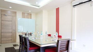 A modern meeting room with a glass table, red chairs, and a whiteboard. - Moritz Hotel Rsab Harapan Kita (Jakarta)