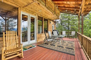 A wooden deck with a glass door leading to a room, outdoor furniture, and a view of trees. - Peaceful Cabin w/ Mtn + River Views, Fire Pit (Garden Valley)