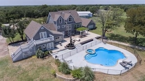 Une grande maison avec une piscine, un patio couvert et une cour clôturée.