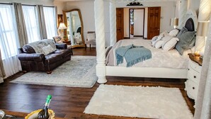 Une chambre à coucher avec un lit à baldaquin, un coin salon avec un canapé et un grand miroir.