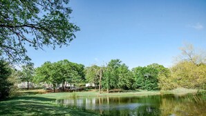 A serene park with a pond, trees, and a clear sky. - Muleshoe Room in Red Oak Lodge @ Towering Oaks b&b (Valley View)