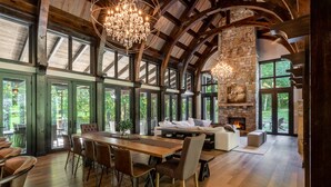 A spacious room with a large wooden dining table, comfortable seating, and a stone fireplace.