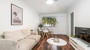 A living room with a beige sofa, a round white coffee table, and a dining area with a white table and chairs.