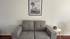 Un sofá gris en una habitación con una fotografía en blanco y negro de una playa en la pared.