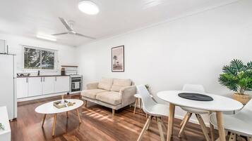 Ein moderner Wohnbereich mit Sofa, Esstisch, Stühlen, einer Küchenzeile und einem Deckenventilator.