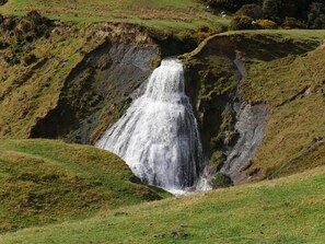 A waterfall cascading down a rocky hillside surrounded by grassy terrain.